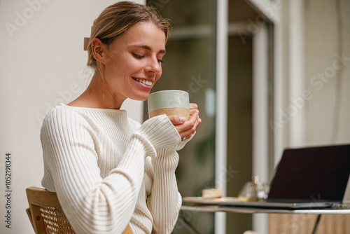 A Cozy Morning A Woman Sitting at Home, Enjoying a Warm Cup of Tea or Coffee Relaxingly photo