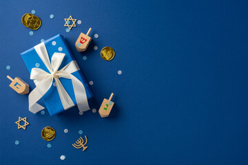 Hanukkah themed image featuring a blue present with white ribbon, wooden dreidels, and gold coins arranged on a blue surface
