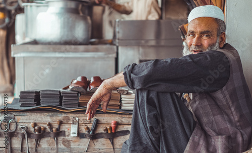 Poor old Pakistani cobbler sitting in his street shop photo