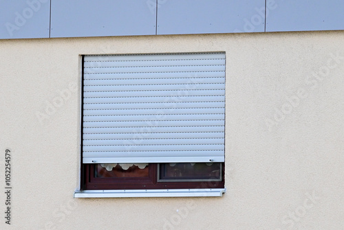 Fenster in einer gelben Hauswand mit halb heruntergelassen Rolladen, Fassade eines Mehrfamilien-Wohnhauses in Niederwerrn, Schweinfurt, Franken, Bayern, Deutschland photo