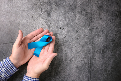 Top view of male hands holding blue ribbon international symbol on dark abstract background. photo