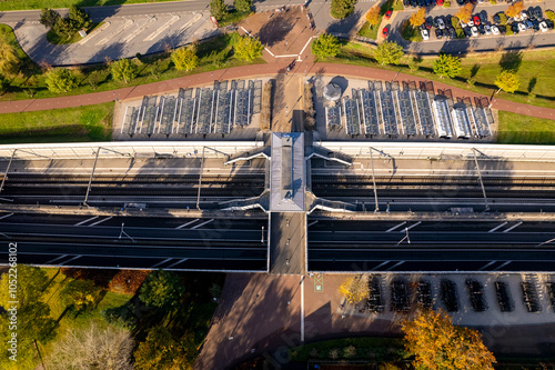 Graphic Dutch railway train station and provincial road coming through countryside landscape tunnel and viaduct. Aerial public transportation infrastructure. Parking lot bicycle stalls. photo