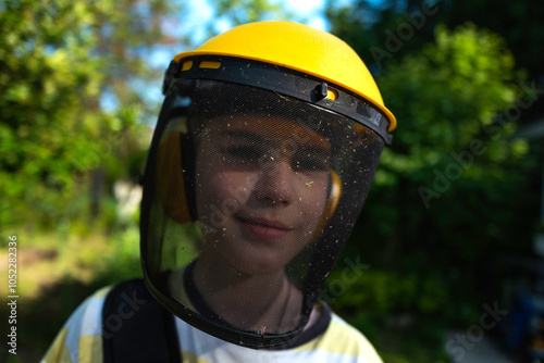 A portrait of a cute boy in a protective mask on the background of a green garden.