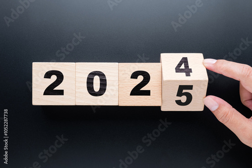 Hand flips the one wood block in the row to to change the year number from 2024 to 2025