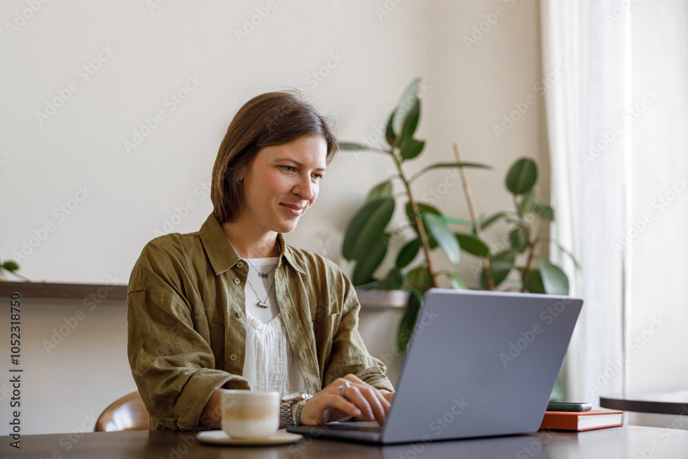 A young woman happily engaged in remote work, smiling brightly while using her laptop in a stylish, welllit space A young woman happily engaged in remote work, smiling brightly while using her laptop in a stylish, welllit space