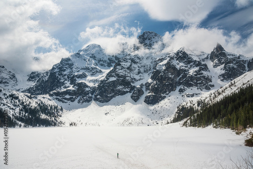 tranquil view of Morskie Oko in Tatra National Park, Poland, showcasing majestic snow-covered mountains, serene frozen lake, and reflections on a chilly winter day. Winter landscape