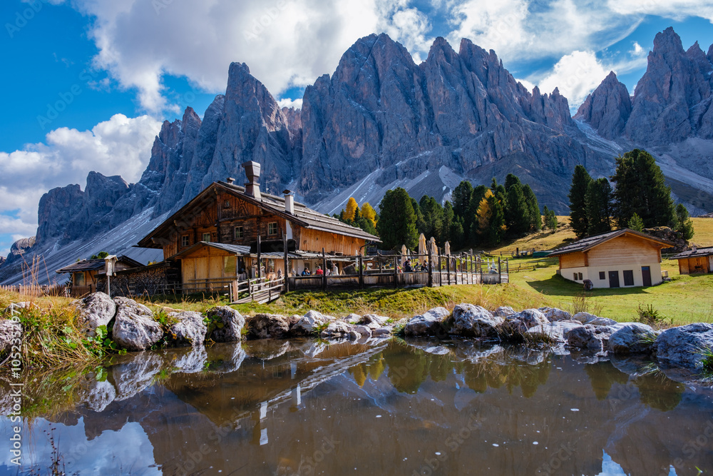 Serene autumn reflection at a rustic cabin in the Dolomites, Italy under a vibrant sky Serene autumn reflection at a rustic cabin in the Dolomites, Italy under a vibrant sky