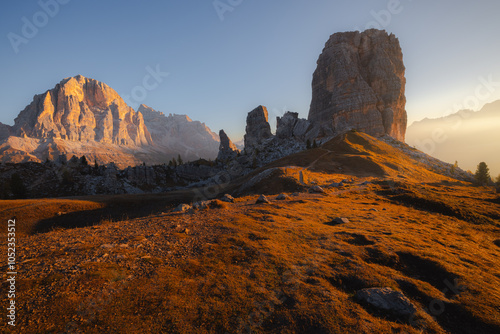 Golden sunrise over Cinque Torri in the Italian Dolomites, showcasing rugged rock formations, panoramic mountain views, and scenic autumn terrain. photo