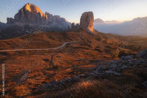 Golden sunrise over Cinque Torri in the Italian Dolomites, showcasing rugged rock formations, panoramic mountain views, and scenic autumn terrain.