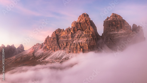 Fototapeta Naklejka Na Ścianę i Meble -  Sunrise or sunset over Tre Cime in the Italian Dolomites with a colourful sky and cloud inversion, showcasing the rugged, majestic peaks and atmospheric beauty of this iconic mountain landscape.