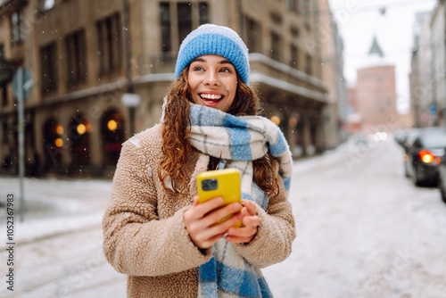 Smiling woman sending message from phone in urban environment. Online communication. Technology concept. photo