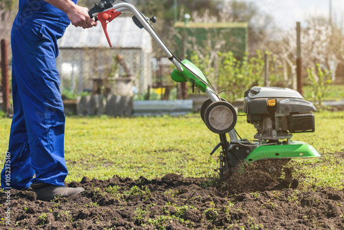 A man engaged in agriculture plows the soil with a cultivator for further planting of vegetables photo