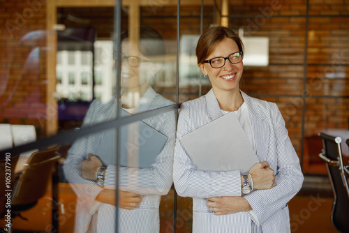 A professional woman is smiling confidently while standing in a modern office environment that is welldesigned photo