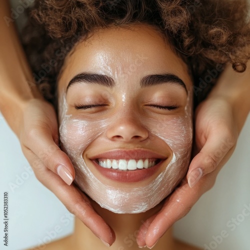 Smiling woman shuts eyes as cosmetologist removes mask. photo