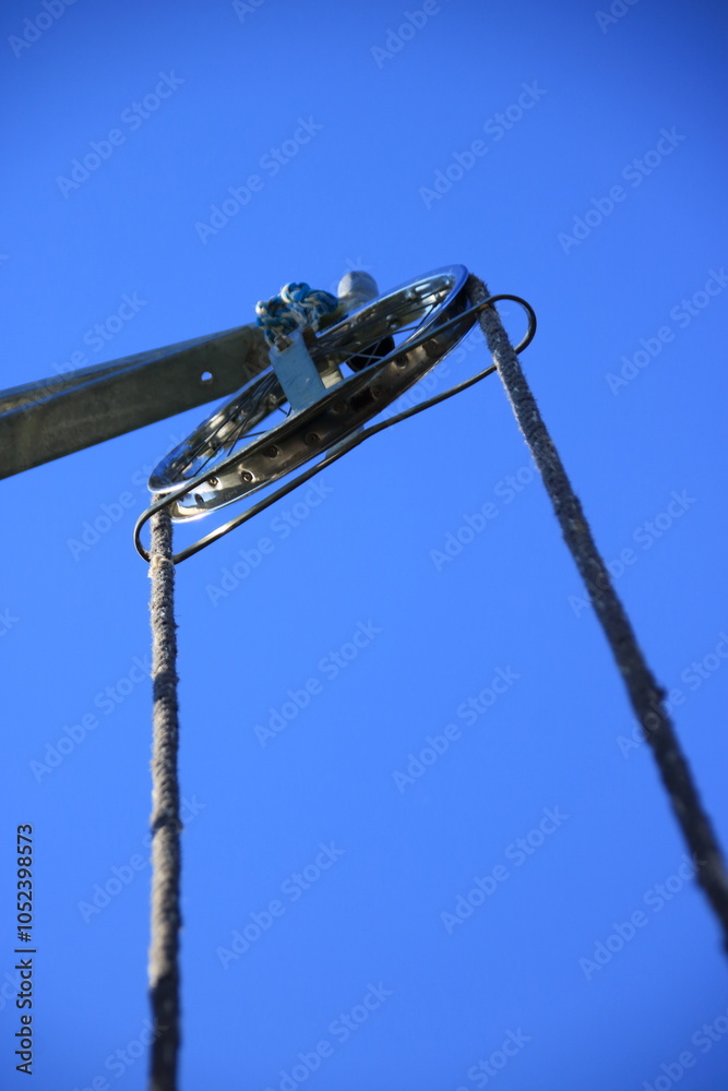 Rundrolle mit Seil zum Heben einer Last auf einer Baustelle von unten fotografiert Rundrolle mit Seil zum Heben einer Last auf einer Baustelle von unten fotografiert