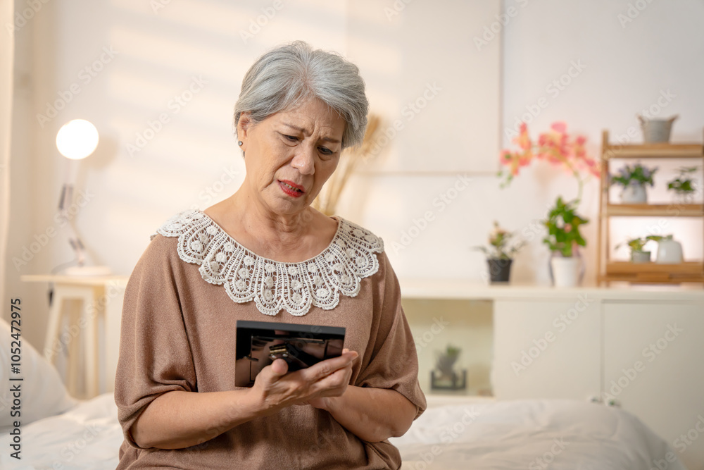 An elderly Asian woman with short white hair is thinking of her loved one, hugging a picture of the person she is missing and crying. An elderly Asian woman with short white hair is thinking of her loved one, hugging a picture of the person she is missing and crying.