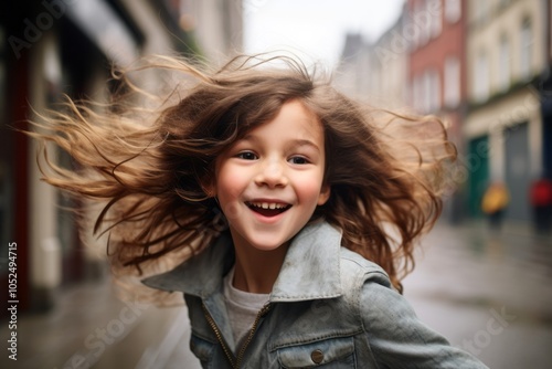 Portrait of a cute little girl with flying hair on the street