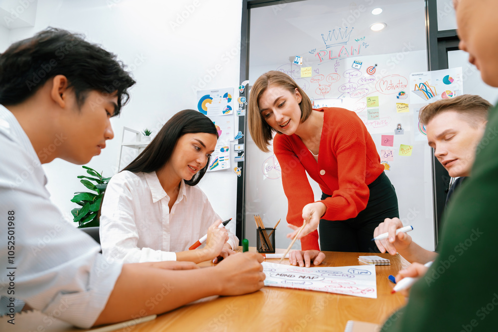 Fototapeta premium Creative happy business team brainstorming and sharing idea by using mind map and graphic graph while young beautiful project manager pointing at important point at business meeting. Immaculate.