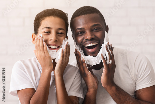 Shaving Fun. Portrait Of Happy African American Father And His Little Son Putting Foam On Their Faces, Having Fun Together, Empty Space photo