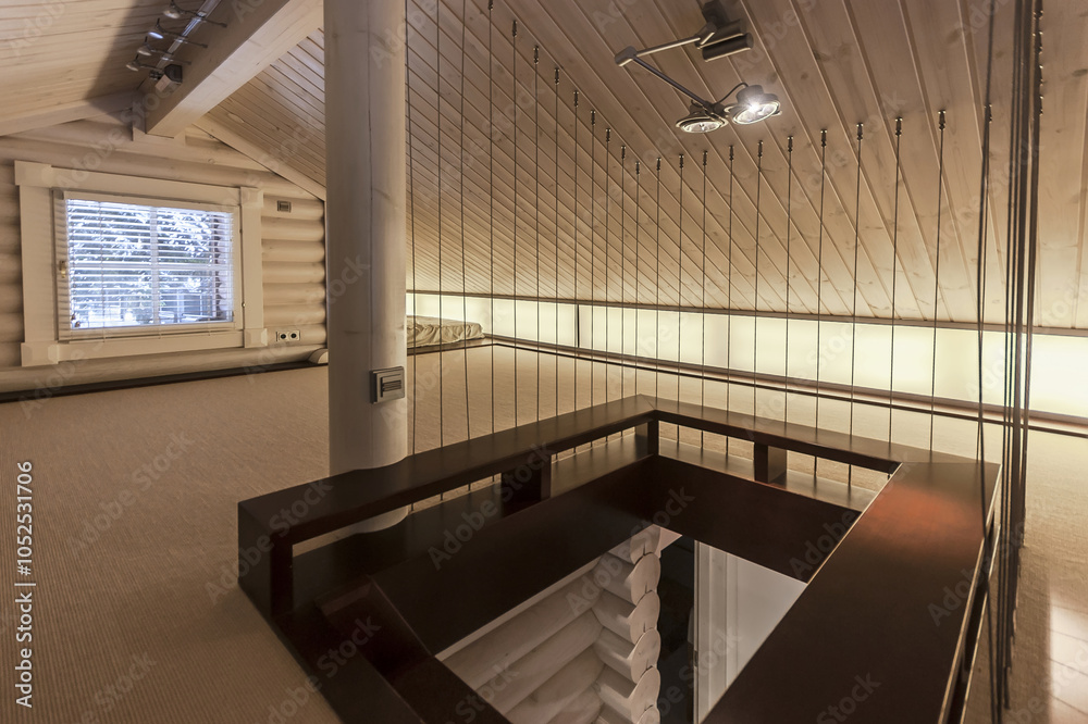 Obraz premium The loft showcases a minimalist design with wooden beams and soft lighting, creating a warm ambiance. Natural light streams through the window, enhancing the modern decor.