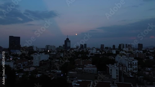 Neighbourhood in Mexico City at sunset in autumn full super moon rises over buildings zoom in camera movement photo