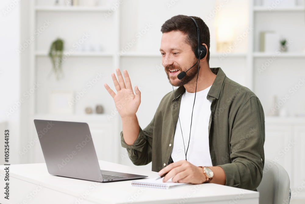 Interpreter in headset having video chat via laptop at white table indoors Interpreter in headset having video chat via laptop at white table indoors