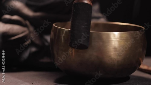A smoldering incense stick in a holder, and a Tibetan singing bowl on a dark background next to the Buddha