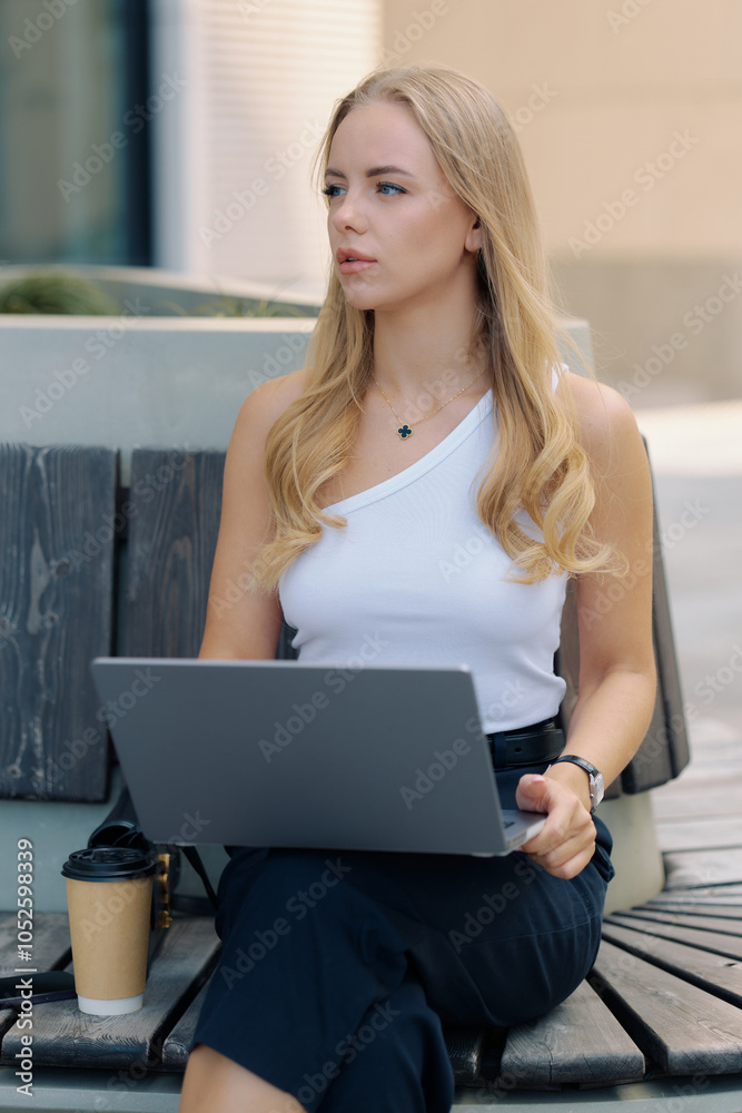 Success concept, well-groomed slim woman sitting on street and waiting for video call on laptop Success concept, well-groomed slim woman sitting on street and waiting for video call on laptop