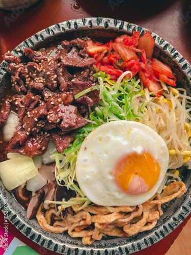 A Korean dish with meat and vegetables and a fried egg photo