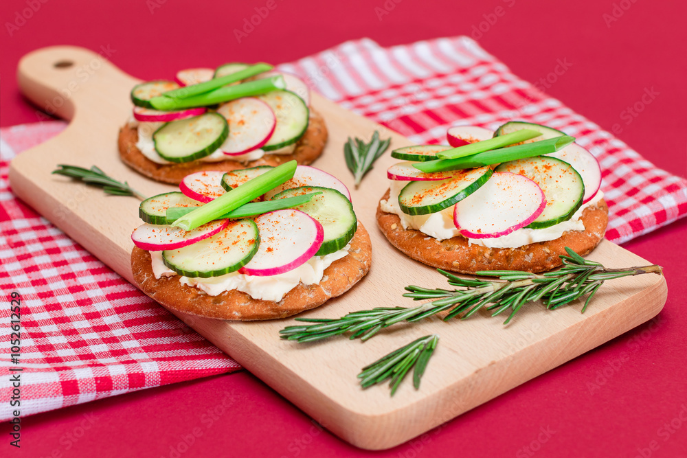 Light Breakfast or Diet Eating - Crispy Cracker Sandwich with Cream Cheese, Fresh Cucumber, Green Onions and Radish on Wooden Cooking Board on Magenta Background Light Breakfast or Diet Eating - Crispy Cracker Sandwich with Cream Cheese, Fresh Cucumber, Green Onions and Radish on Wooden Cooking Board on Magenta Background