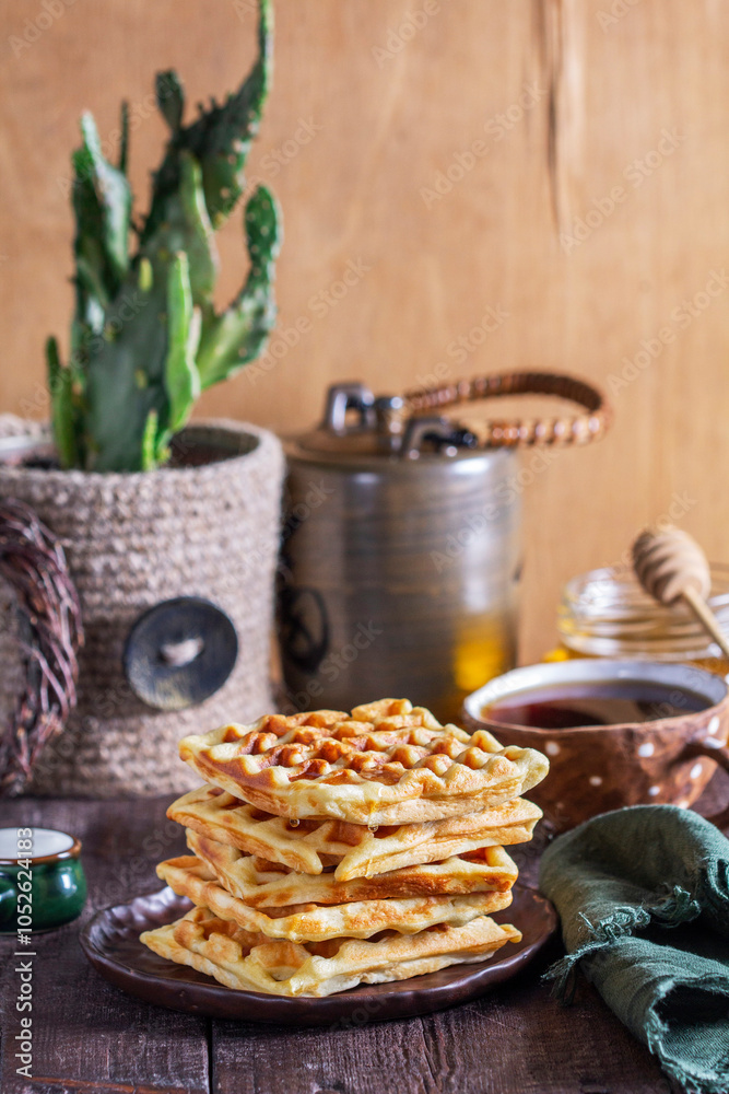 Belgian waffles served with honey, cream and sai on a wooden background. Rustic style.