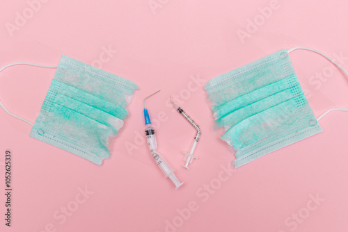 Anti Vaccine Movement and Anti Mask Concept - Broken Medical Syringe and Green Torn Medical Face Mask on the Pink Background. Pandemic and Lockdown End - Top View, Flat Lay photo