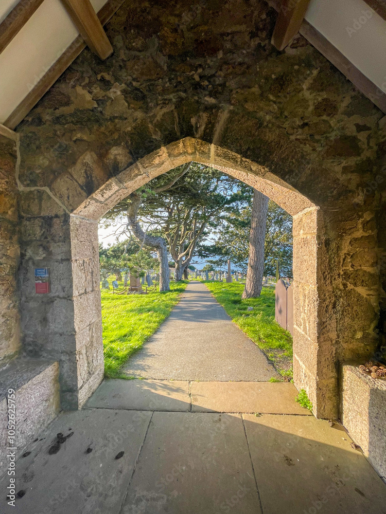 Obraz premium Tudor arch in Wales leading to trees and grave yard.
