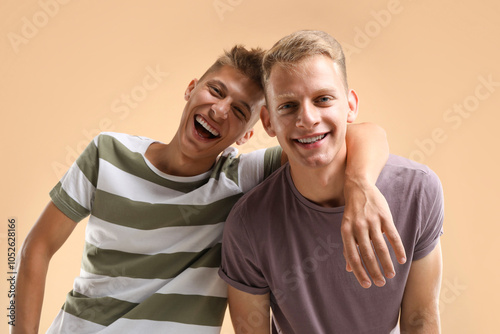 Portrait of happy brothers on beige background