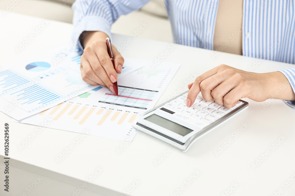 Fototapeta premium Budget planning. Woman with papers using calculator at white table, closeup
