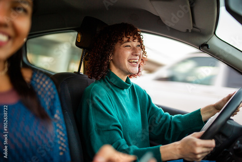 Cuadro en lienzo Smiling woman driving car with friend in passenger seat