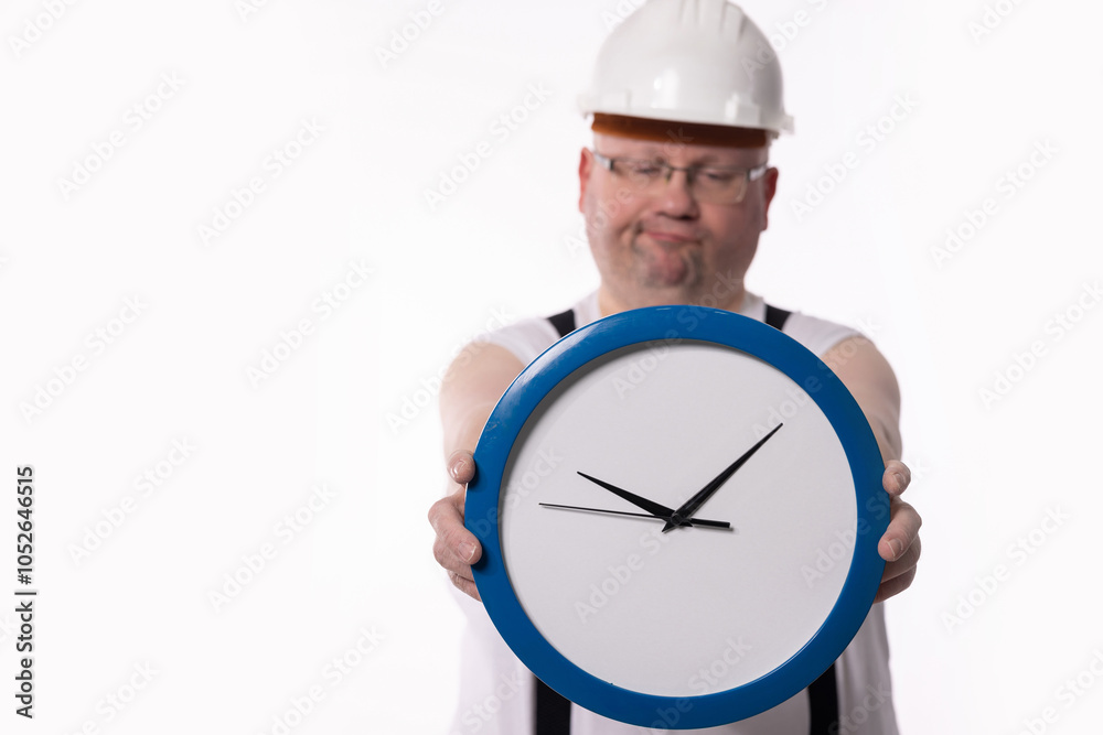 A Determined Worker Holding a Clock While Wearing Construction Gear at the Job Site A Determined Worker Holding a Clock While Wearing Construction Gear at the Job Site