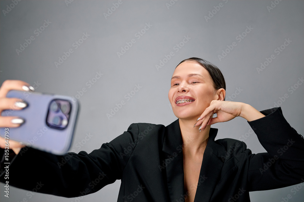Portrait of a well-groomed woman with braces taking a selfie on her phone Portrait of a well-groomed woman with braces taking a selfie on her phone