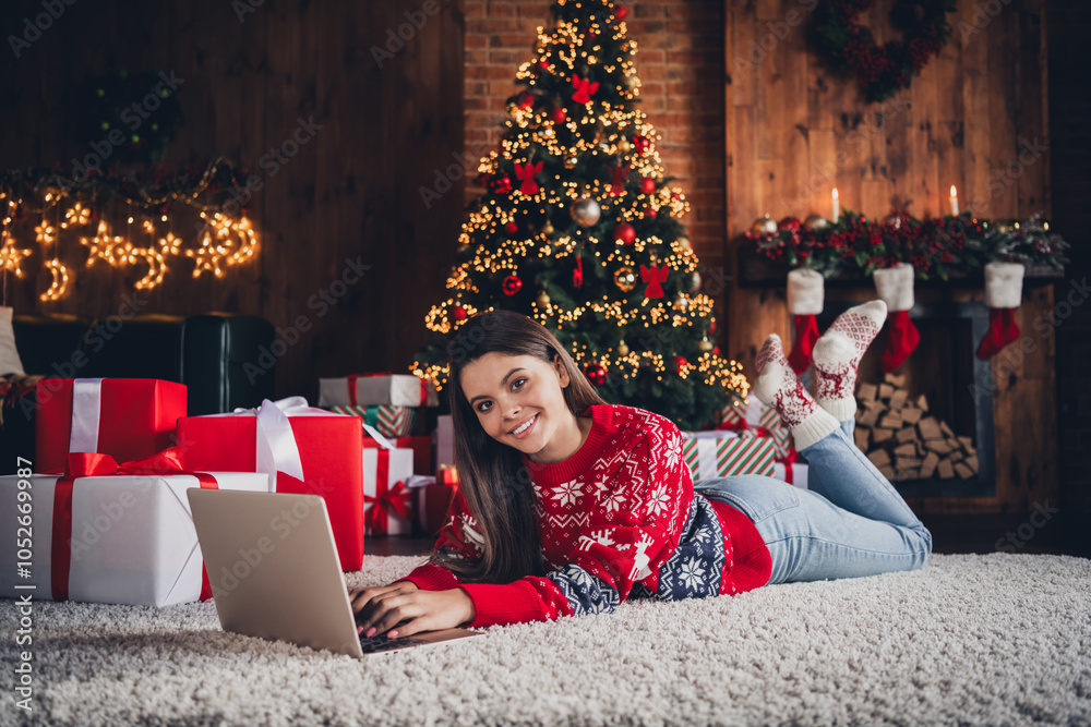 Photo of pretty sweet girl wear new red clothes lying on carpet enjoying christmas festive time weekend decorated room indoors