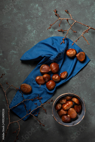 A bowl with edible chestnuts stands on a blue cloth