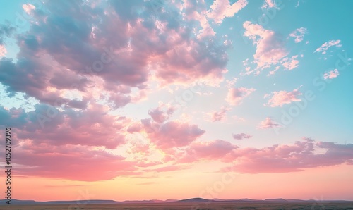 A stunning display of a colorful sky with soft, fluffy clouds during sunset or twilight above an open landscape