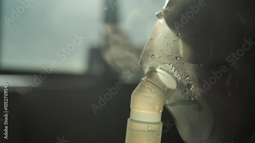 Close-up of a child wearing a plastic oxygen mask on his face inhaling his lungs with a nebulizer compressor. Treatment of the bronchi with bronchitis, pneumonia and asthma by inhalation