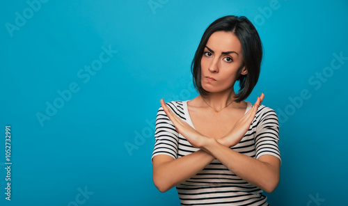 A young woman in a striped shirt crosses her arms in an 