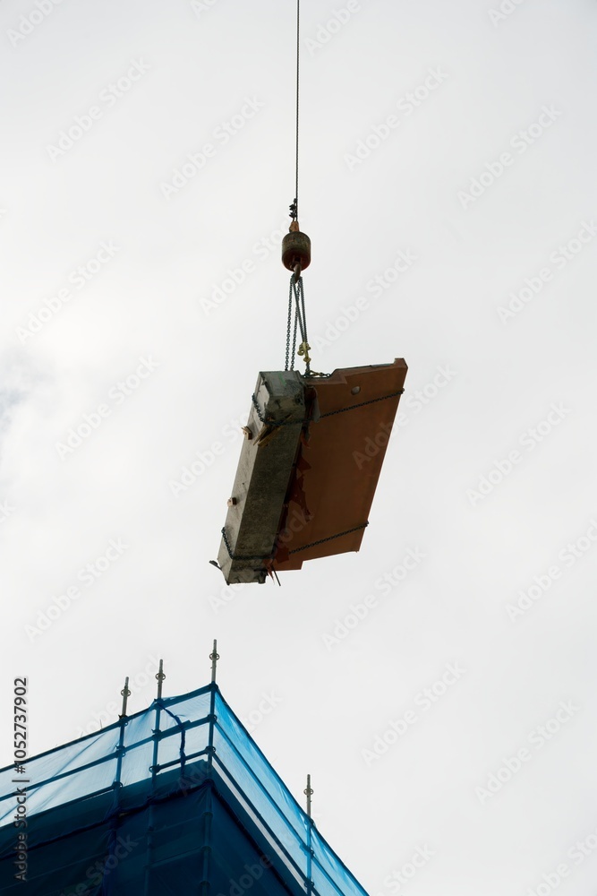 Large Concrete Debris on Crane Hook: Construction Site Scene with Scaffolding Large Concrete Debris on Crane Hook: Construction Site Scene with Scaffolding