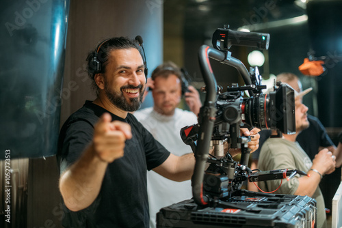 Director of photography with a camera in his hands on the set. Professional videographer at work on filming a movie, commercial or TV series. Filming process indoors, studio