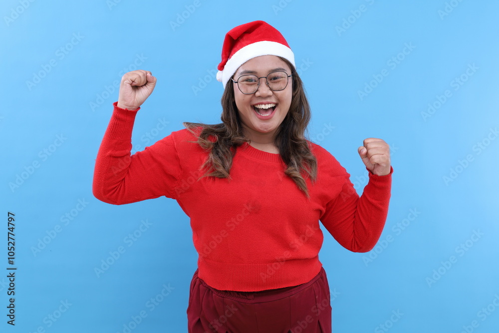 Merry young Asian woman wear red turtleneck hat posing doing winner gesture celebrate clenching fists say yes isolated blue background. Happy New Year 2025 celebration Christmas holiday concept Merry young Asian woman wear red turtleneck hat posing doing winner gesture celebrate clenching fists say yes isolated blue background. Happy New Year 2025 celebration Christmas holiday concept