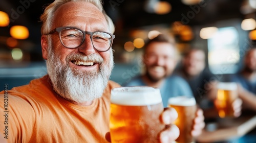 An older man with a white beard and glasses, wearing an orange shirt, revels in a lively pub environment while enjoying a cold, frothy beer with friends.