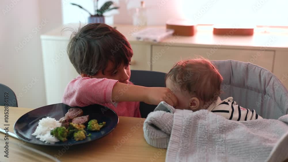 Young boy reaching out to baby during family meal, gentle gesture, sibling bond, shared moments at dining table, connection and care between children, warm atmosphere Young boy reaching out to baby during family meal, gentle gesture, sibling bond, shared moments at dining table, connection and care between children, warm atmosphere