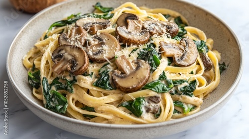 A plant-based pasta dish with a creamy cashew Alfredo sauce, topped with mushrooms and spinach.