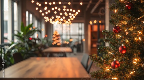 A Christmas tree with red balls on it is in a room with a table and chairs